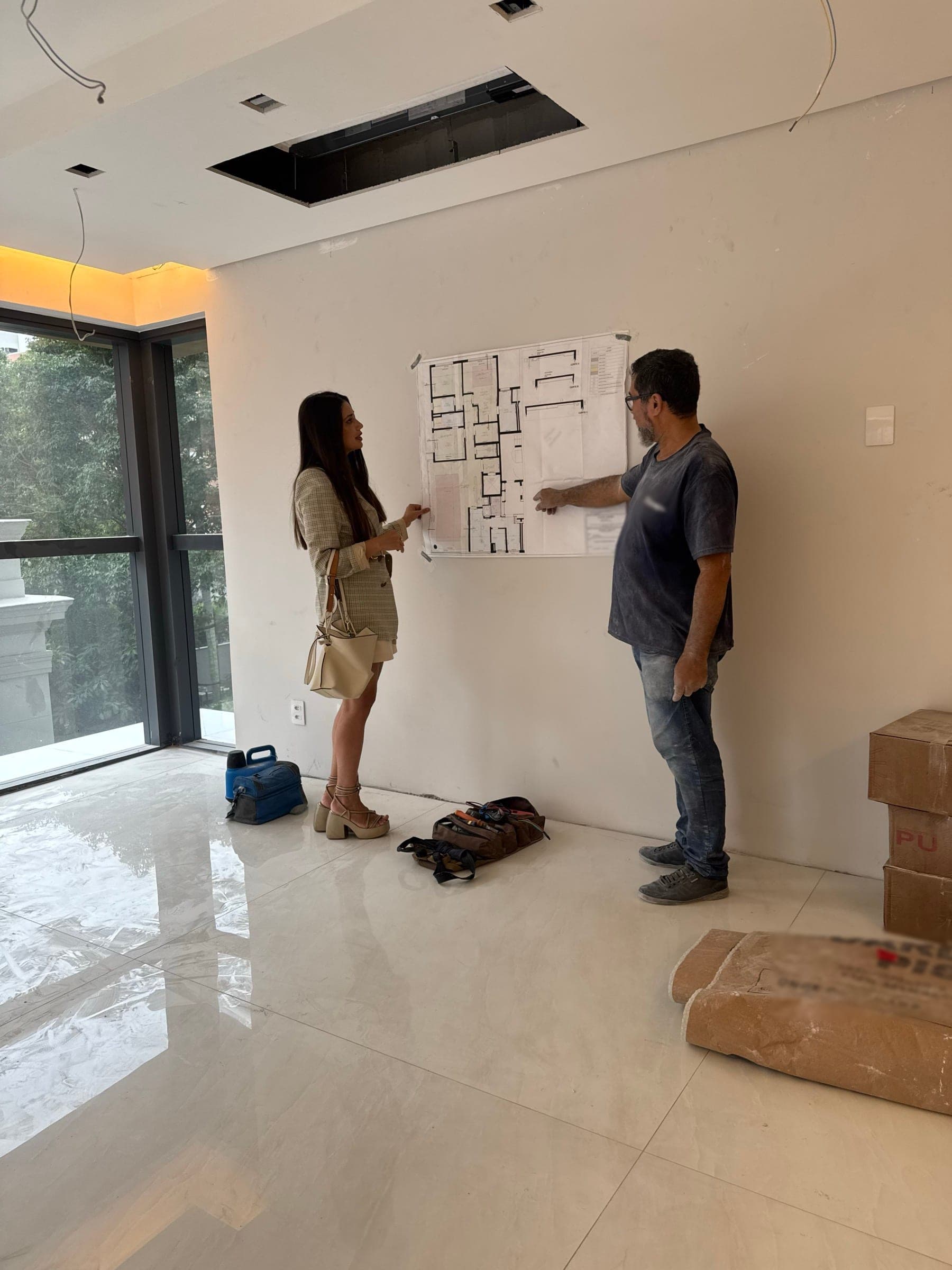 An architect and a contractor going over the floor plan taped to the wall, on site