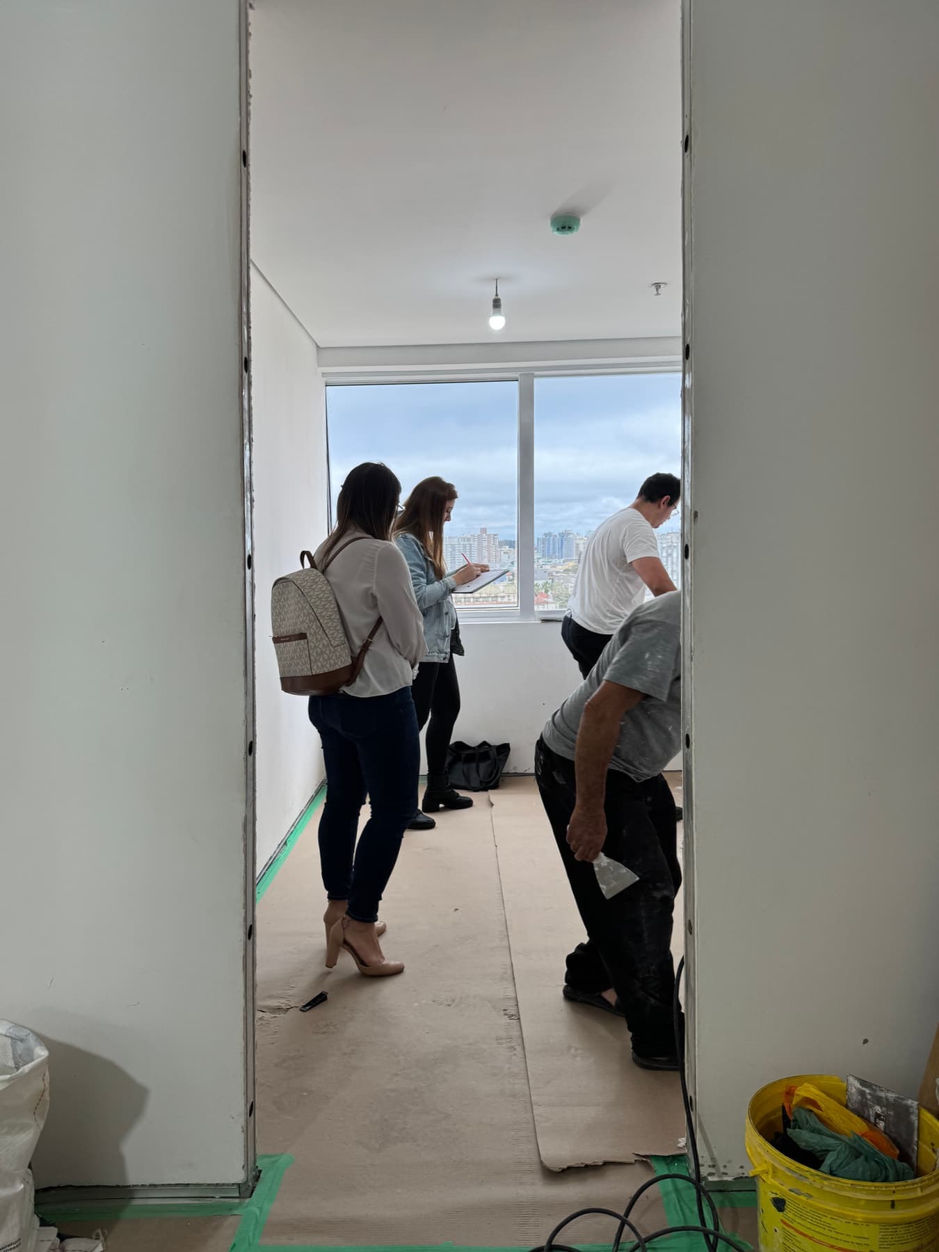 The team and the client in a room on site; one of them takes notes on a clipboard by the window